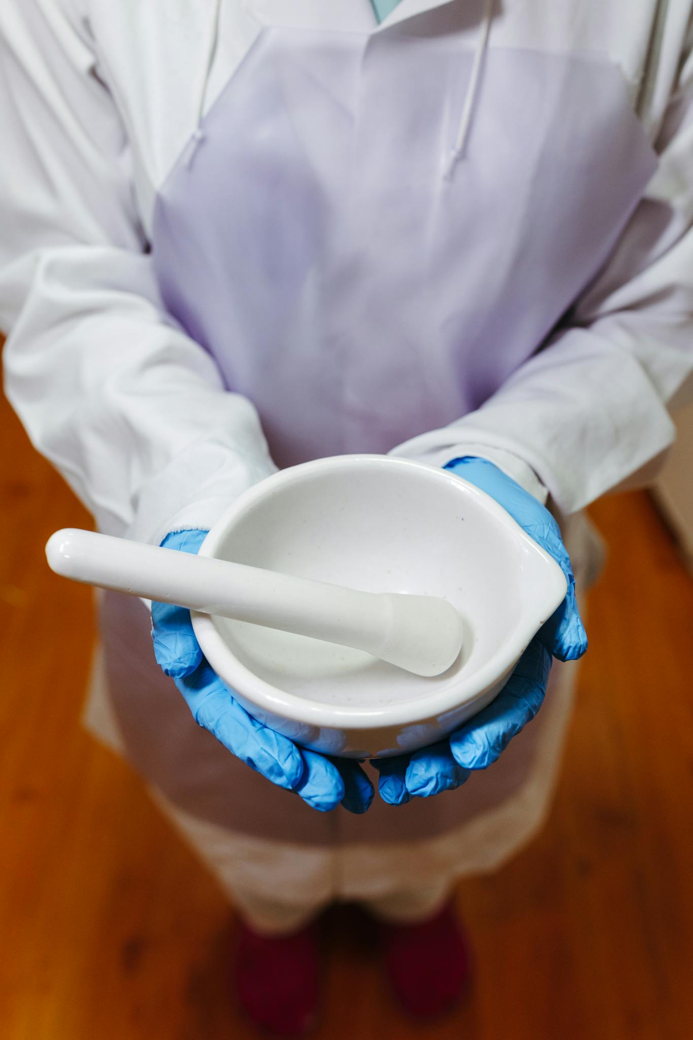 Close-up of a pharmacist holding white mortar and pestle in lab attire