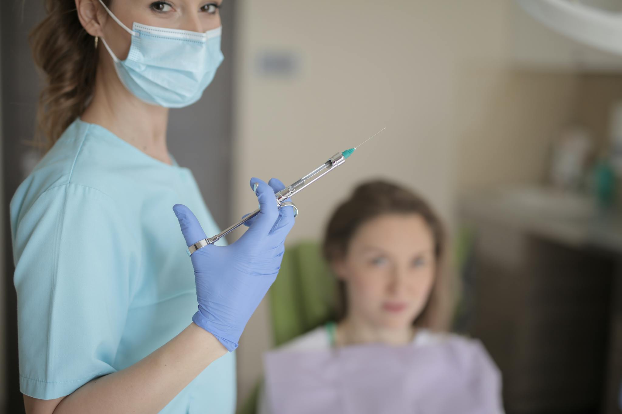 Dentist holding a syringe in clinic, preparing for a dental procedure.