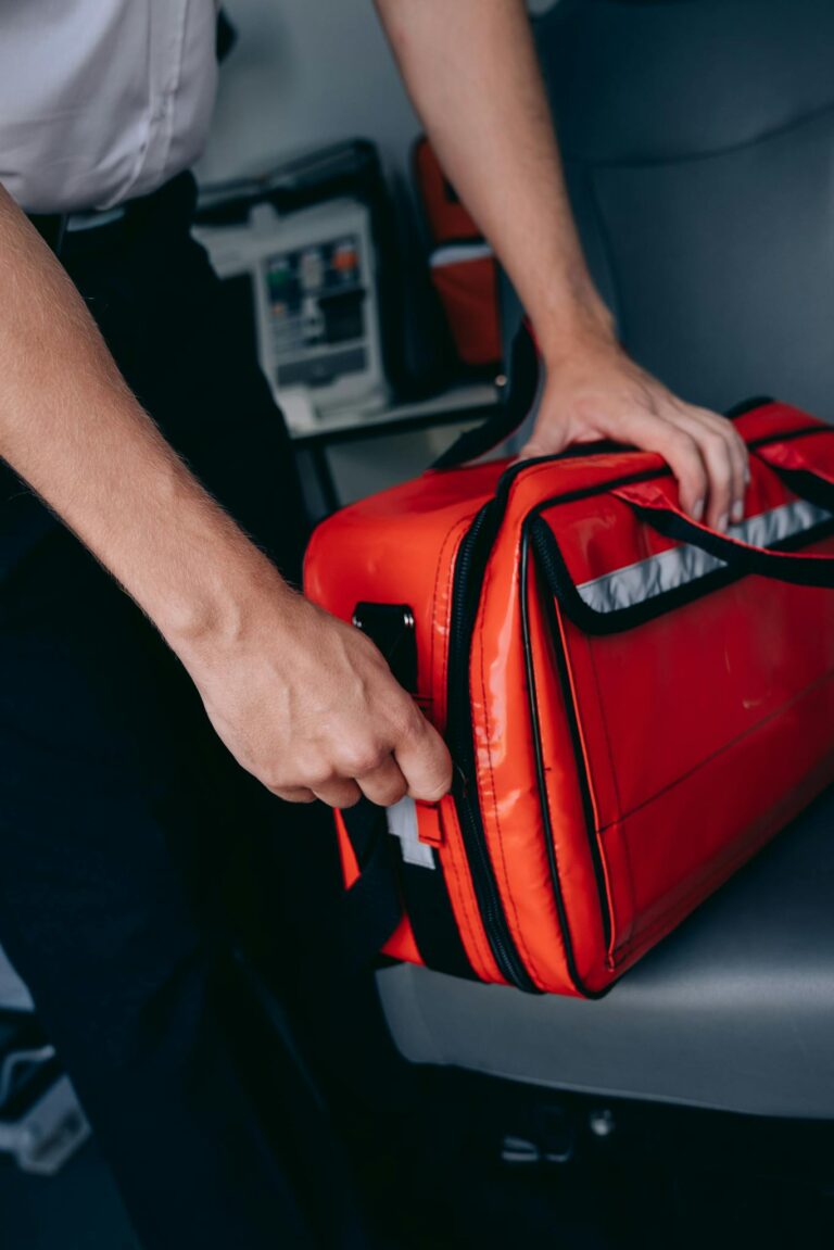 Paramedic opening a bright red emergency medical bag inside a vehicle for quick access to medical supplies.